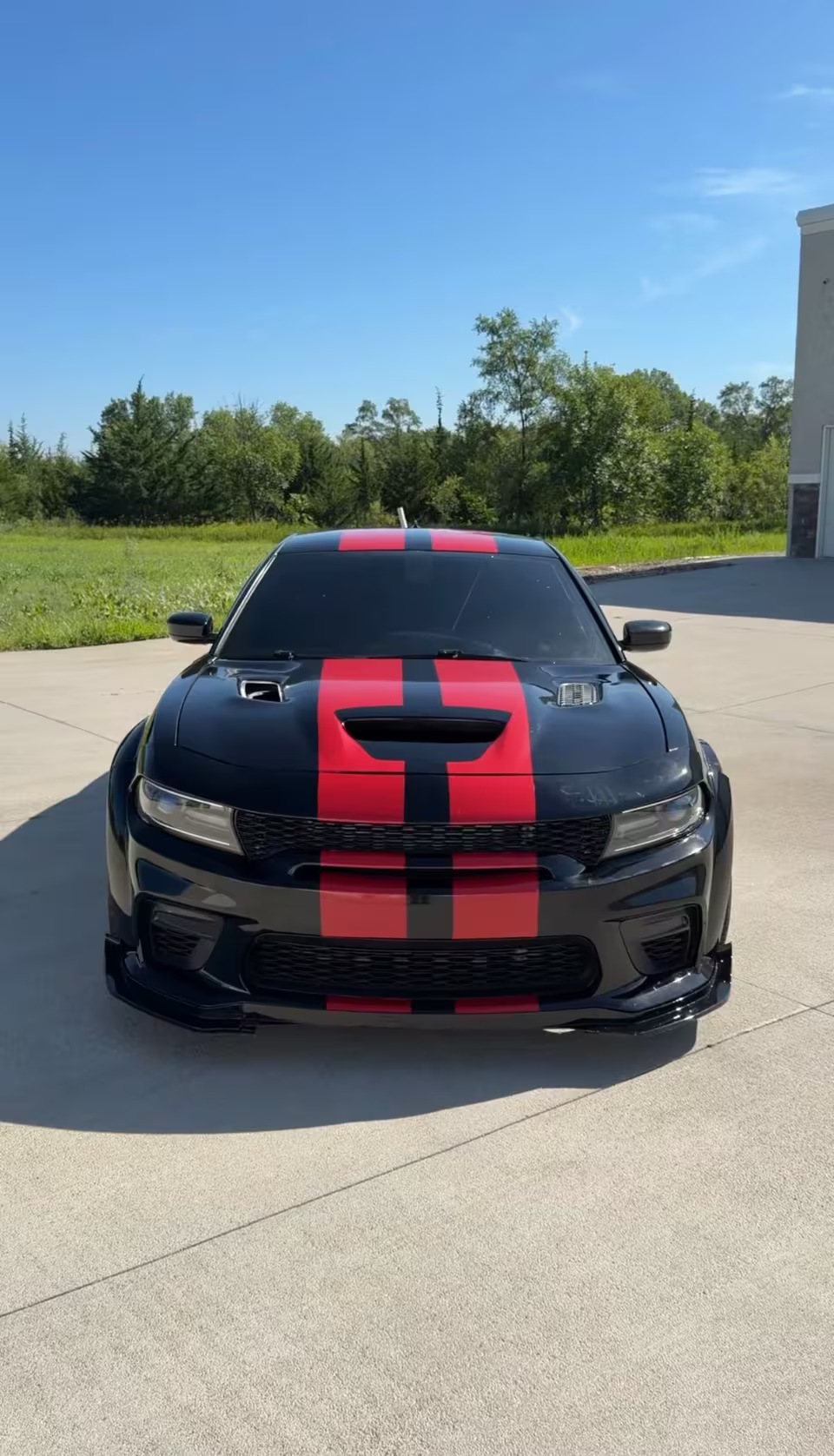 Black Dodge Charger with red racing stripes and tinted windows
